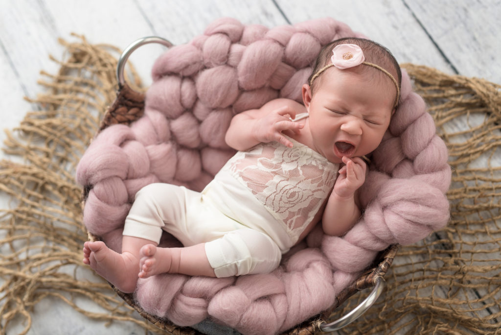 Sleep newborn in white lace outfit yawn
