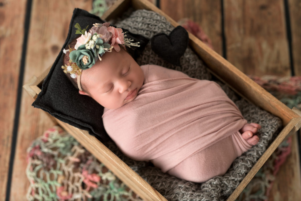 Newborn girl pink flowers in wood prop