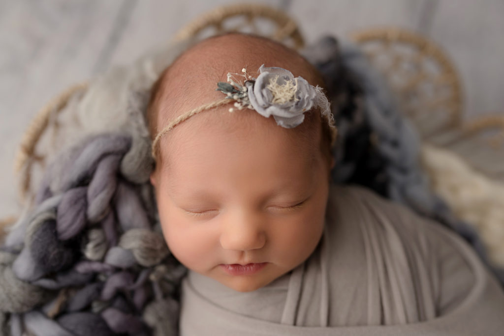 Close up of newborn baby girl face with gray flower headband