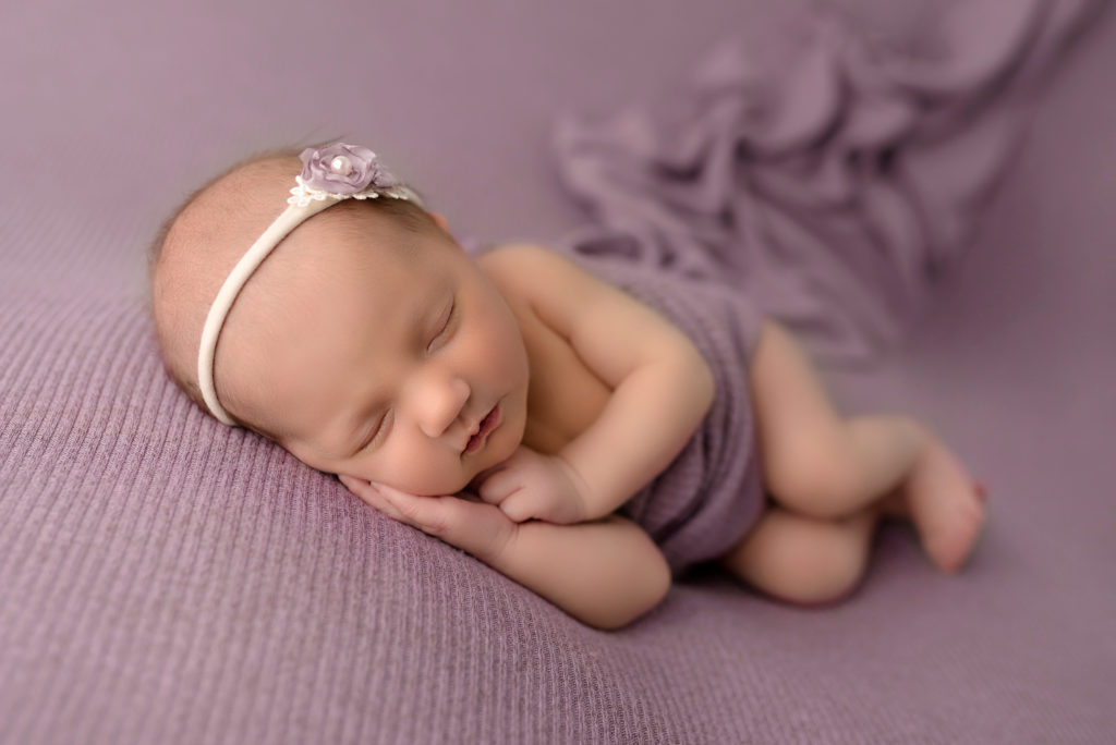 Newborn Girl in charlotte studio on purple side laying sleeping posed