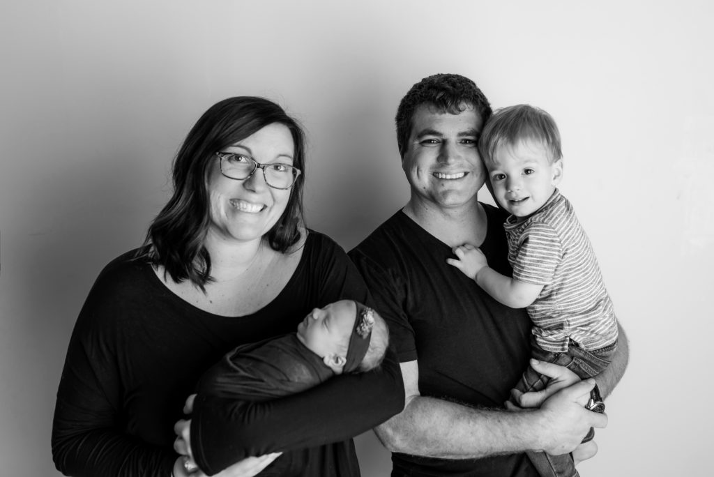 Family studio posed photo with toddler and newborn smiles BW
