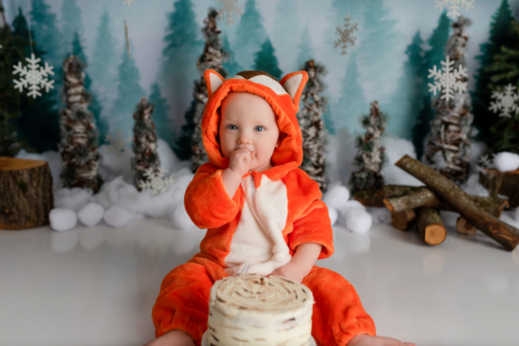 Happy boy with fox outfit and hood eating cake for cake smash session