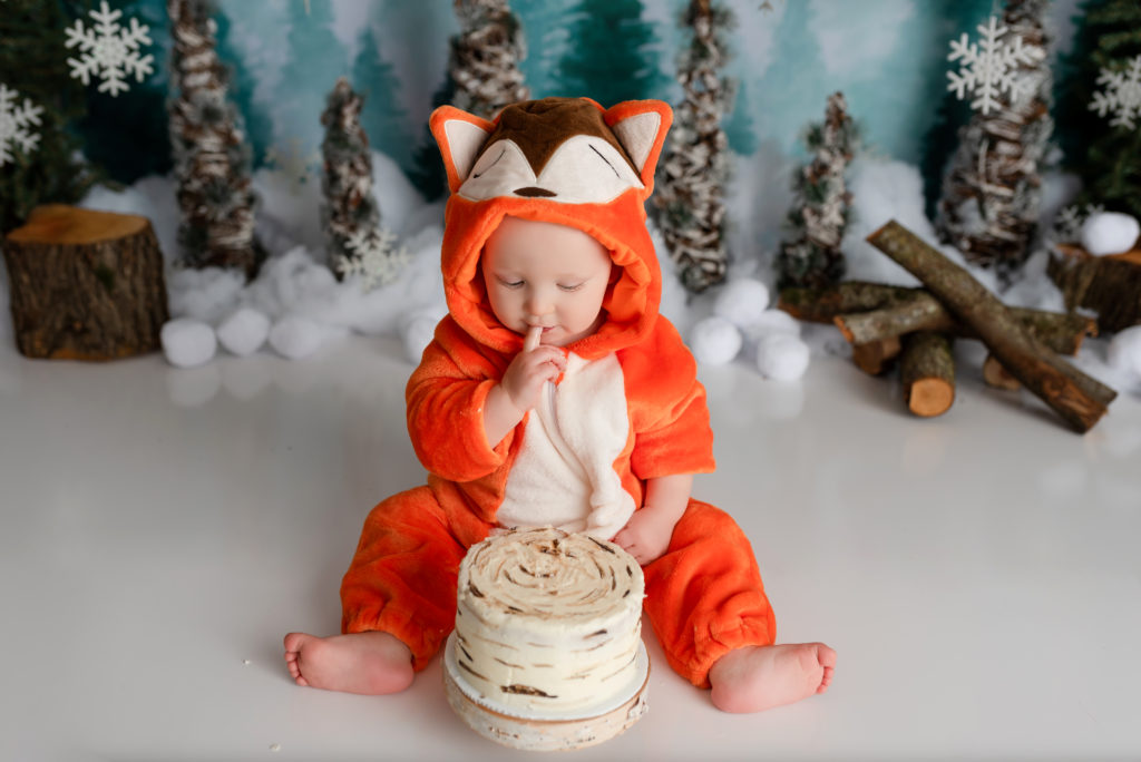 Cake Smash with baby in fox outfit looking at birch cake decorated cake