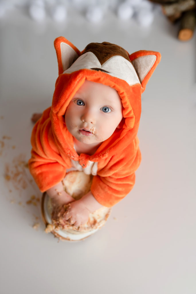 Orange fox costume on baby boy for smash cake looking at camera