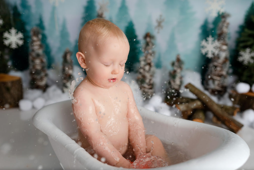 Baby splashing in bath tub on winter theme smash photography in studio