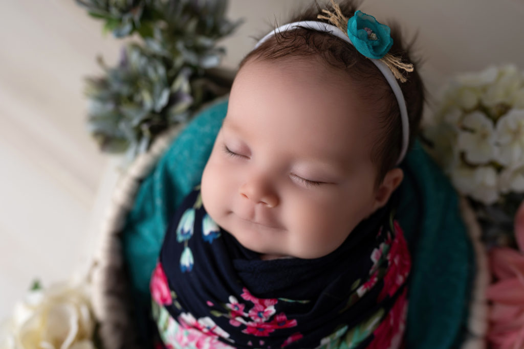 Newborn Baby smiling sleepy posed with flowers bright colors