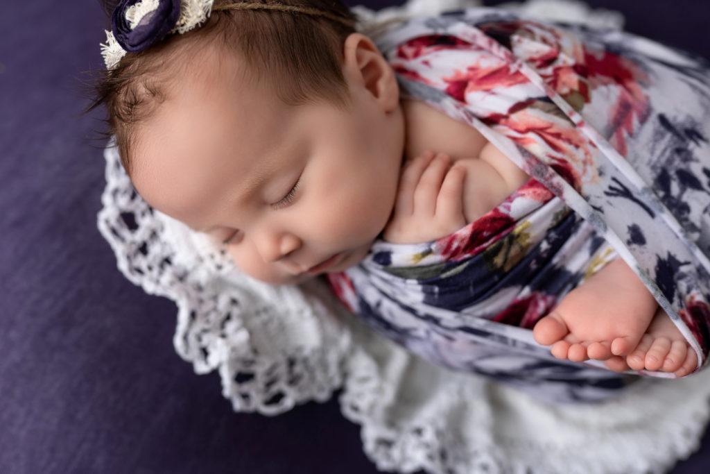 Newborn girl wrapped in studio toes out purple