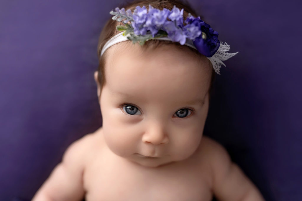 Sweet baby girl eyes looking at camera with purple floral headpiece