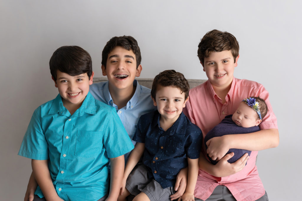 Boys sitting with baby sister for family newborn photo shoot