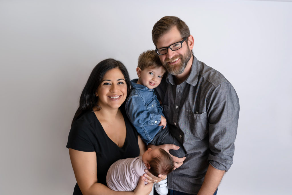 Smiling family photo in newborn studio with baby girl and toddler