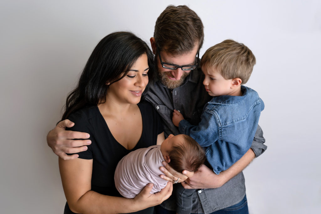 family wrapped together smiling at baby in studio photo session
