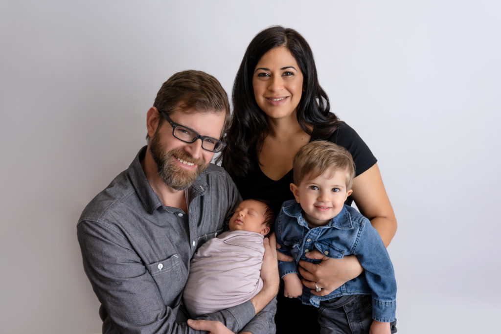 family of 4 posed in studio with baby girl and big brother