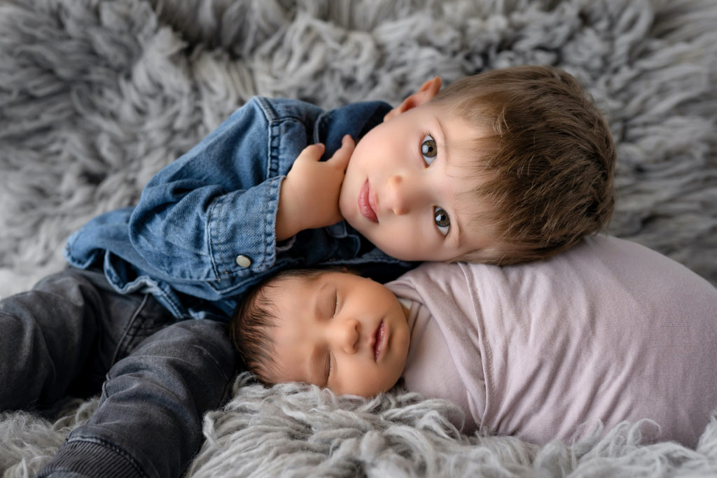 Sibling snuggles together for posed newborn photo