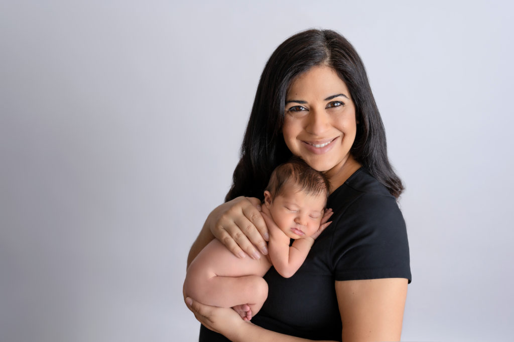 Mama smiling with newborn girl nude on chest posed photography