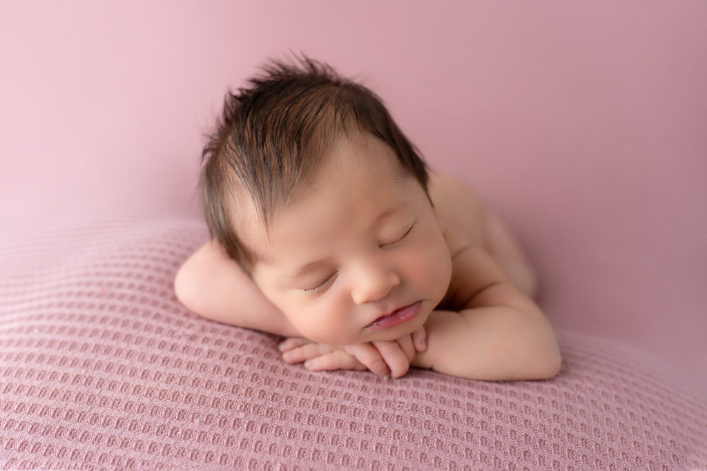 chin on hands baby girl on pink in studio newborn photography
