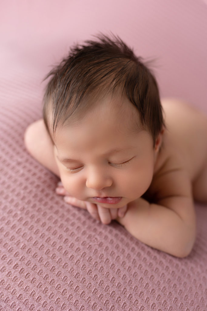 posed newborn girl on mauve backdrop