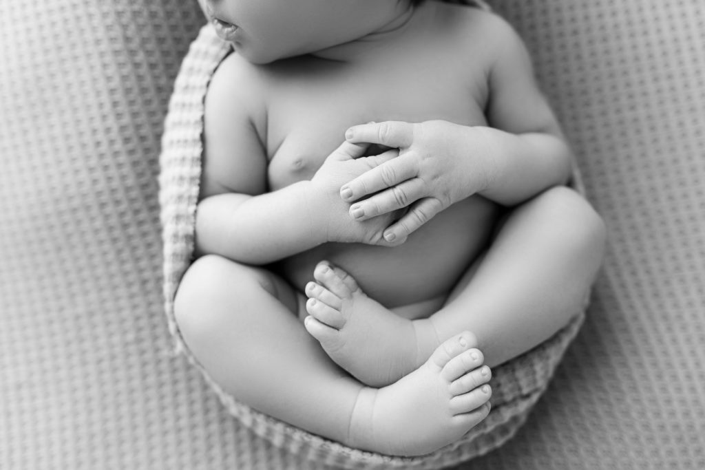 baby hands and feet close up wrapped in textured swaddled BW