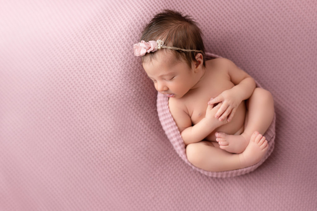 baby girl wrapped on pink overhead posed photographer