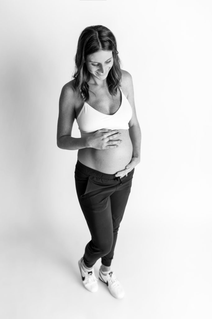 smiling mom holding belly posed for studio maternity Charlotte