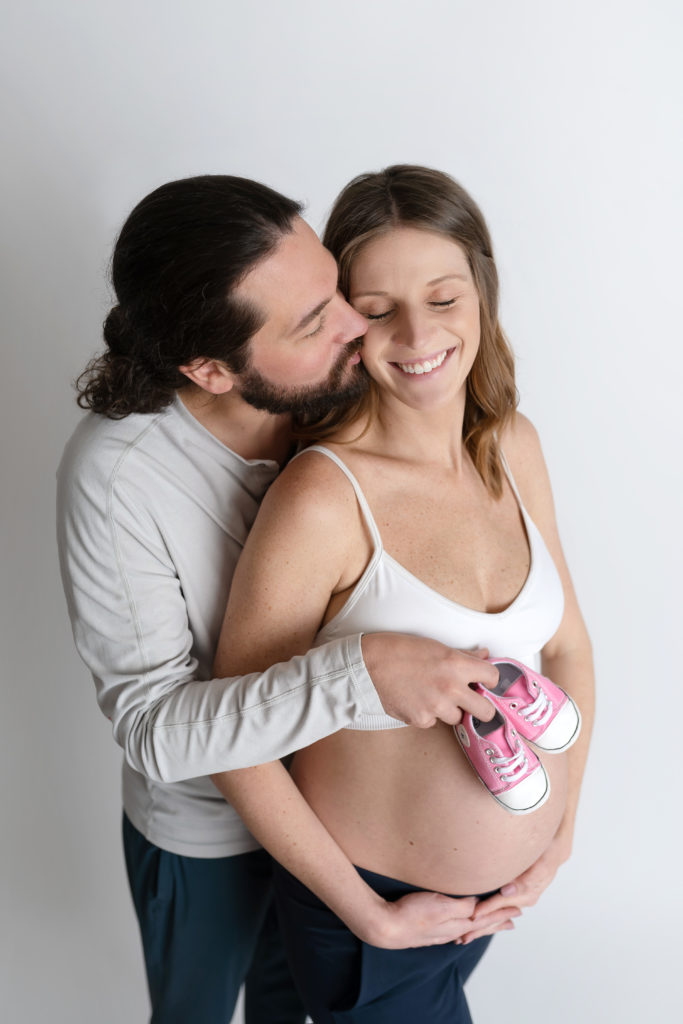 dad holding baby shoes posed in studio with mom Charlotte