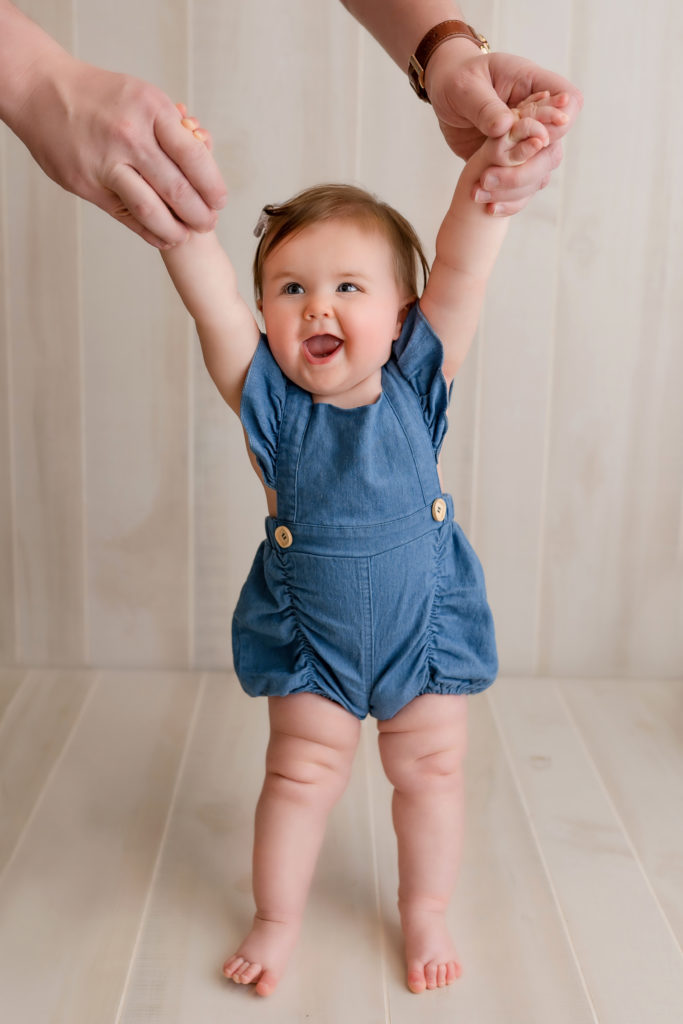 joyful baby girl standing up for photograph in studio session