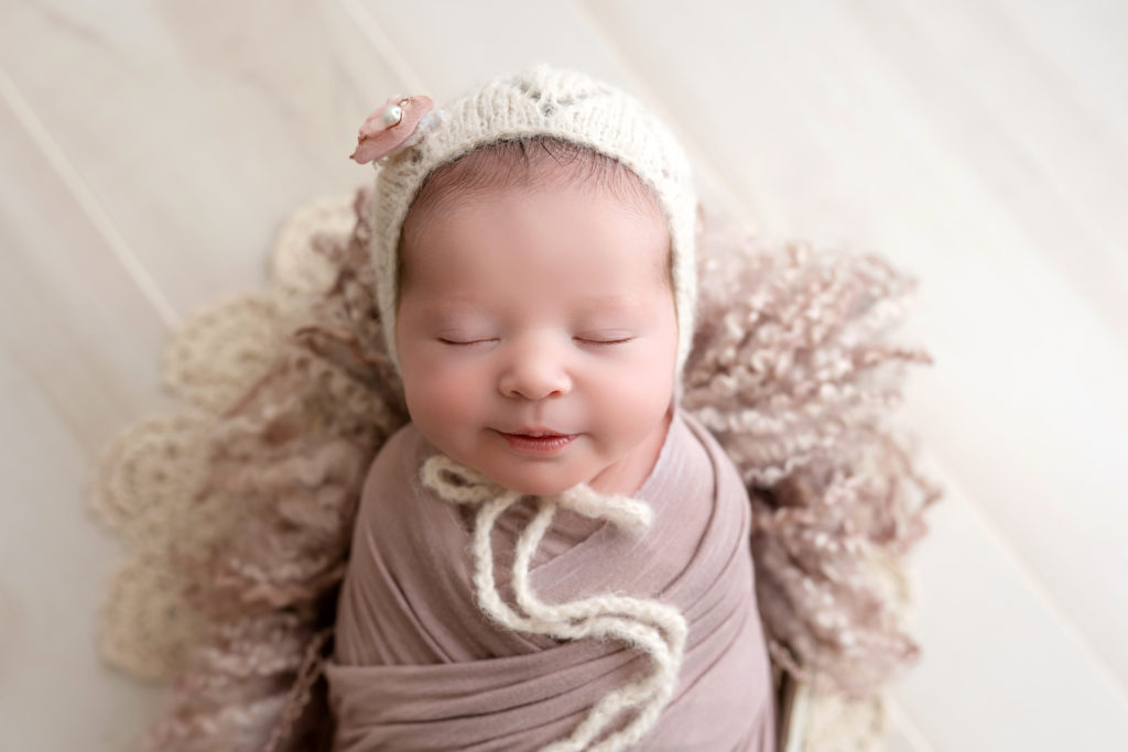 beautiful smiling newborn baby wrapped for studio posed