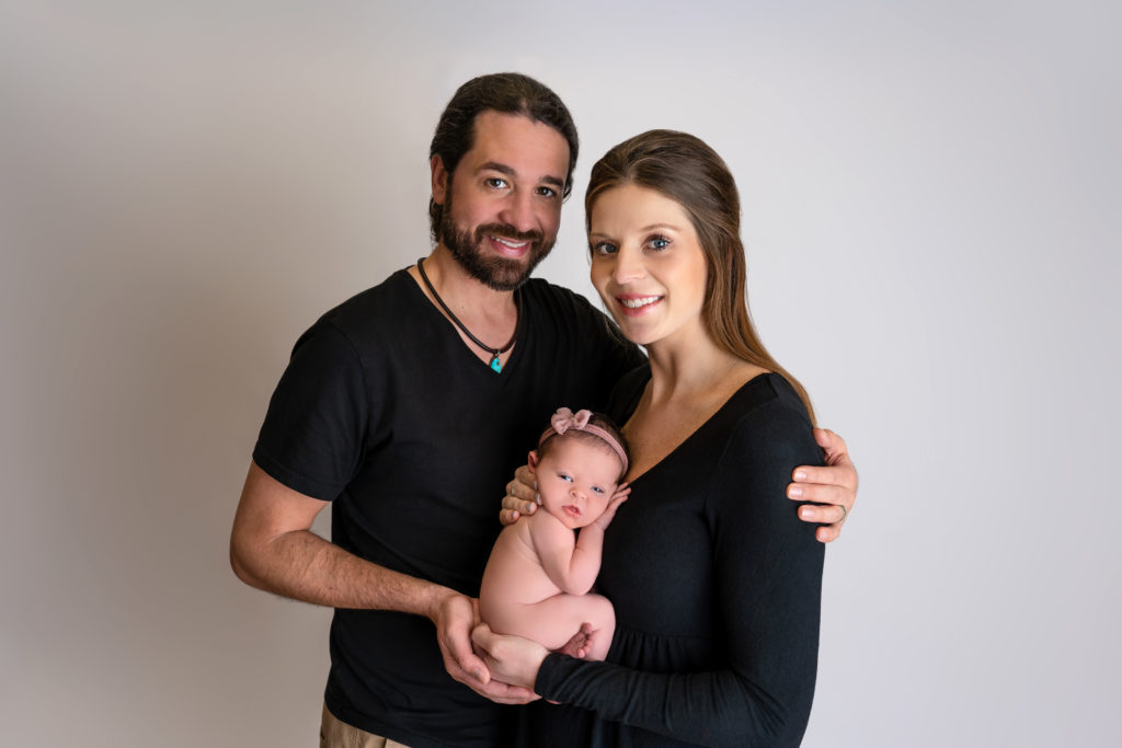 newborn baby girl posed with beaming parents in studio Indian Trail