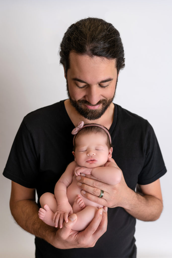 proud dad holding newborn baby posed in studio Charlotte