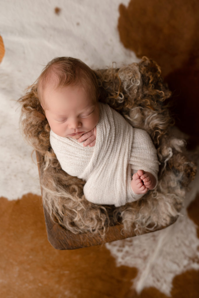furry swaddle baby in white on fluffy chair 