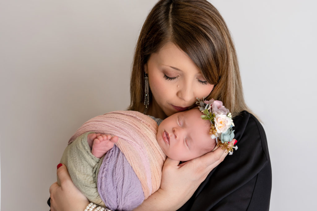 newborn with new mother holding asleep baby in hands completely swaddled photogarphy