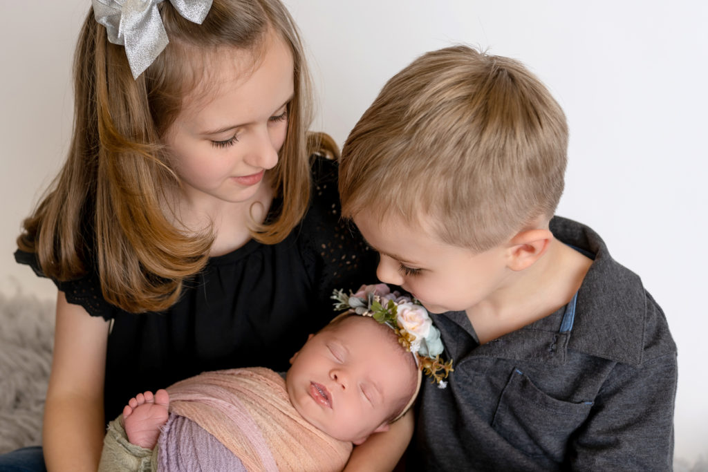Studio photography with newborn and brother and sister looking down