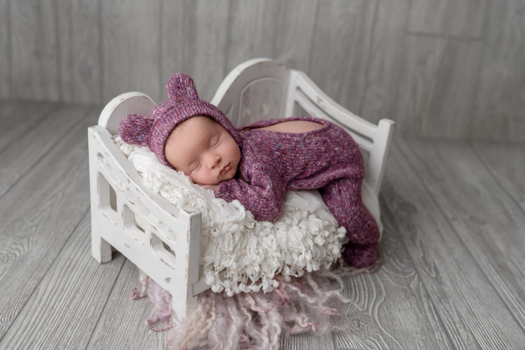 asleep newborn purple outfit in white tiny bed beautiful