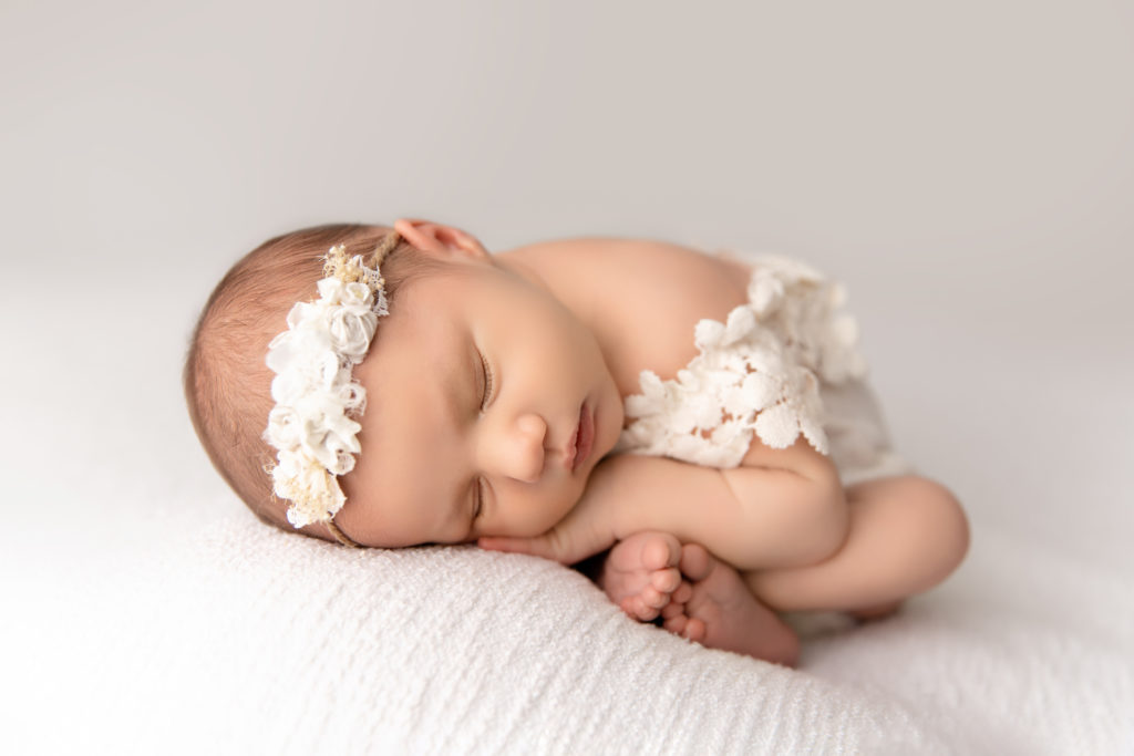 newborn sleeping in white dress and headband