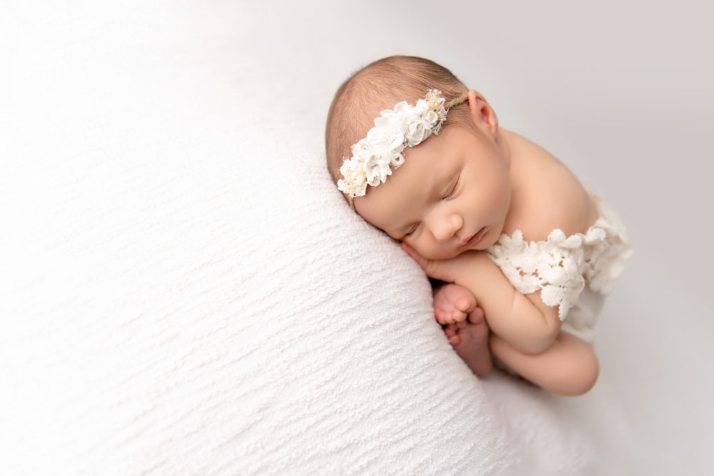 newborn laying asleep with headband and white dress