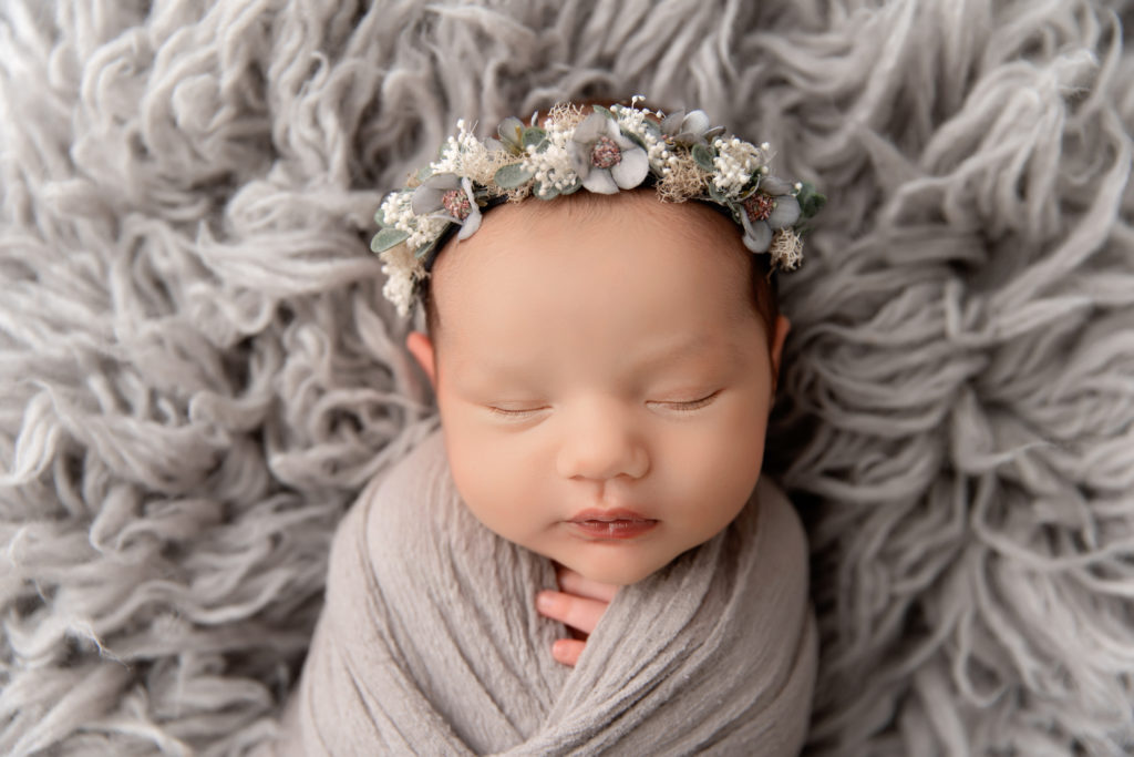 close up of newborn sleeping in gray wrap