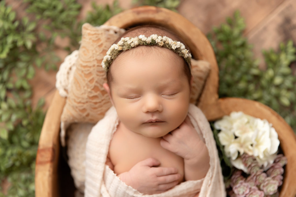 newborn in heart shaped bowl with headband