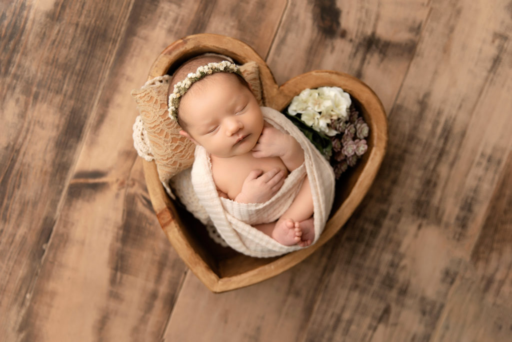 newborn posed in heart shaped bowl