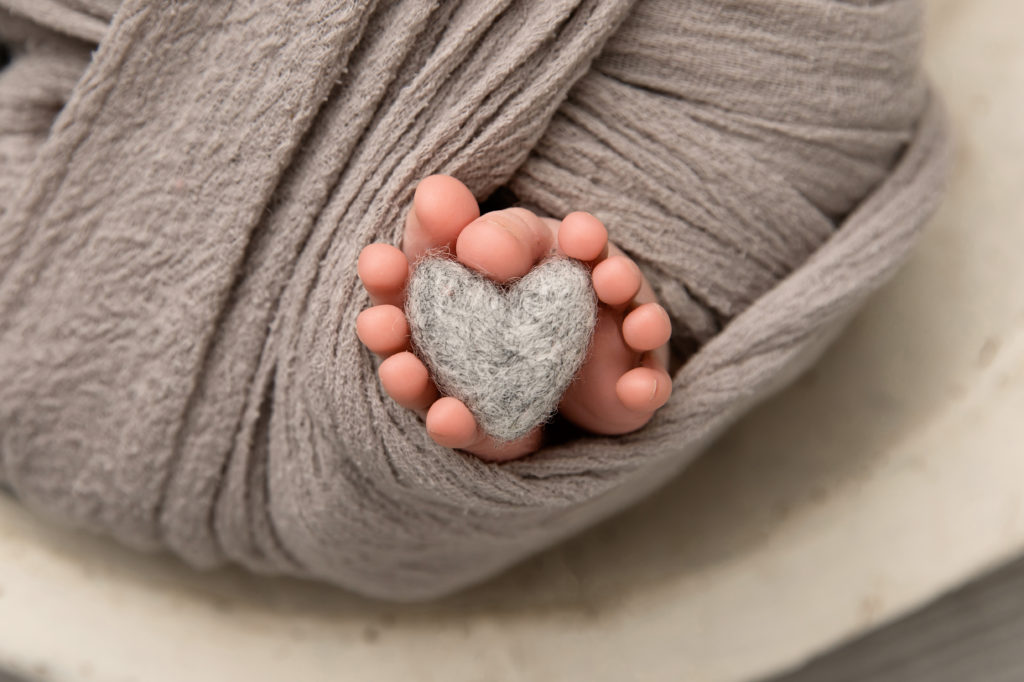 newborn toes holding gray heart
