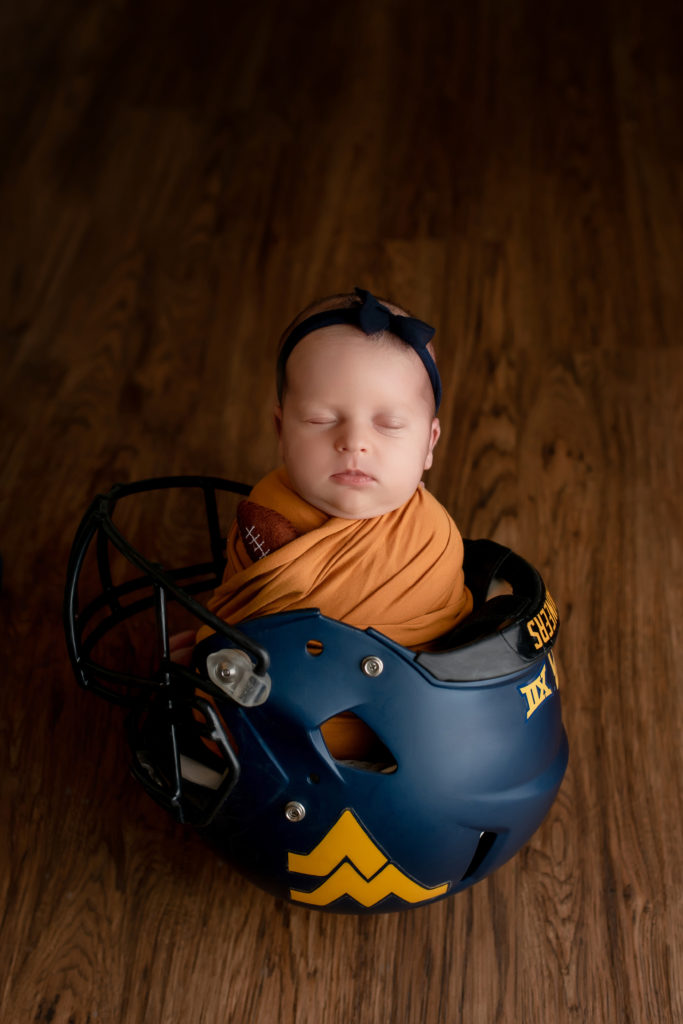Newborn in football helmet.