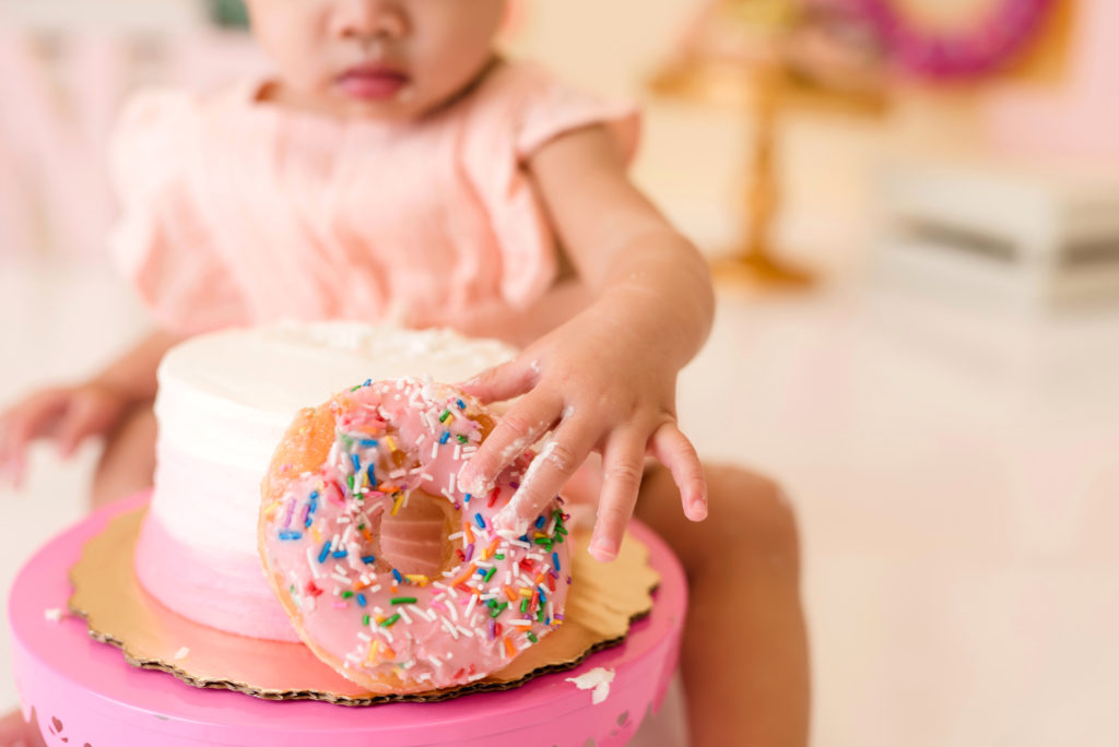 Pink donut with sprinkles on cake,