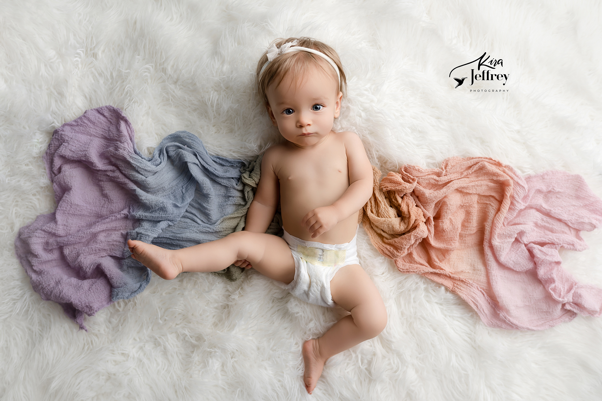 Baby girl milestone photography with rainbow wrap on white blanket