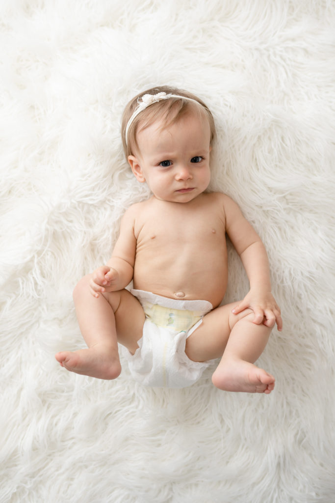 Funny baby look on white fuzz in diaper newborn photographer 