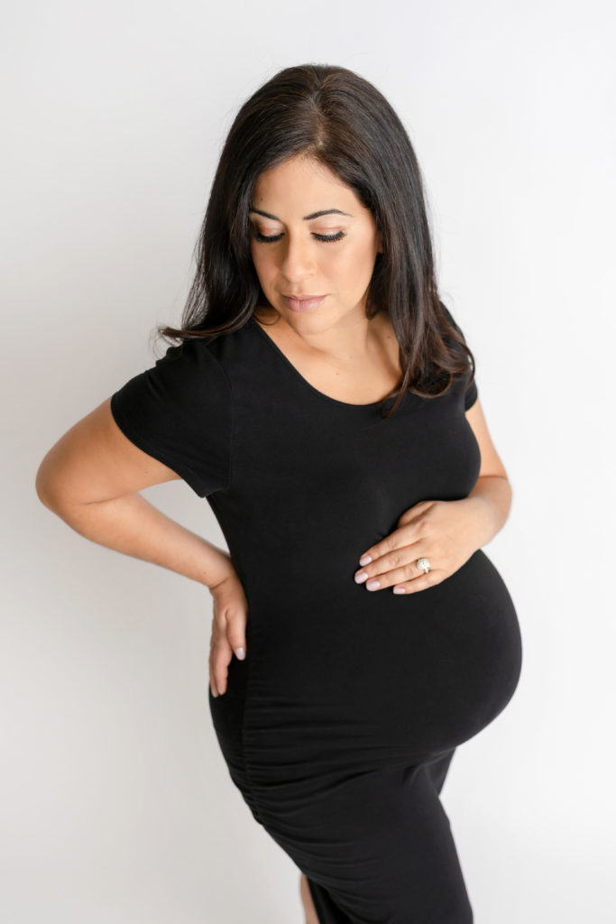 posed expecting mama in black dress looking down
