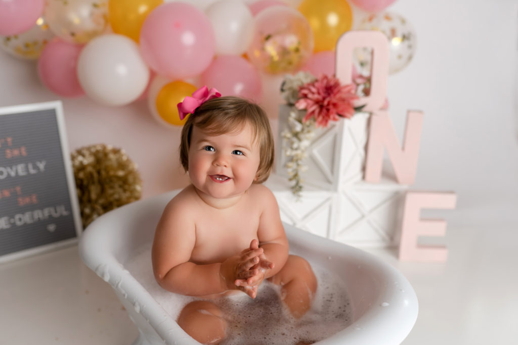 Splash bath after cake smash baby girl smiling with pink bow
