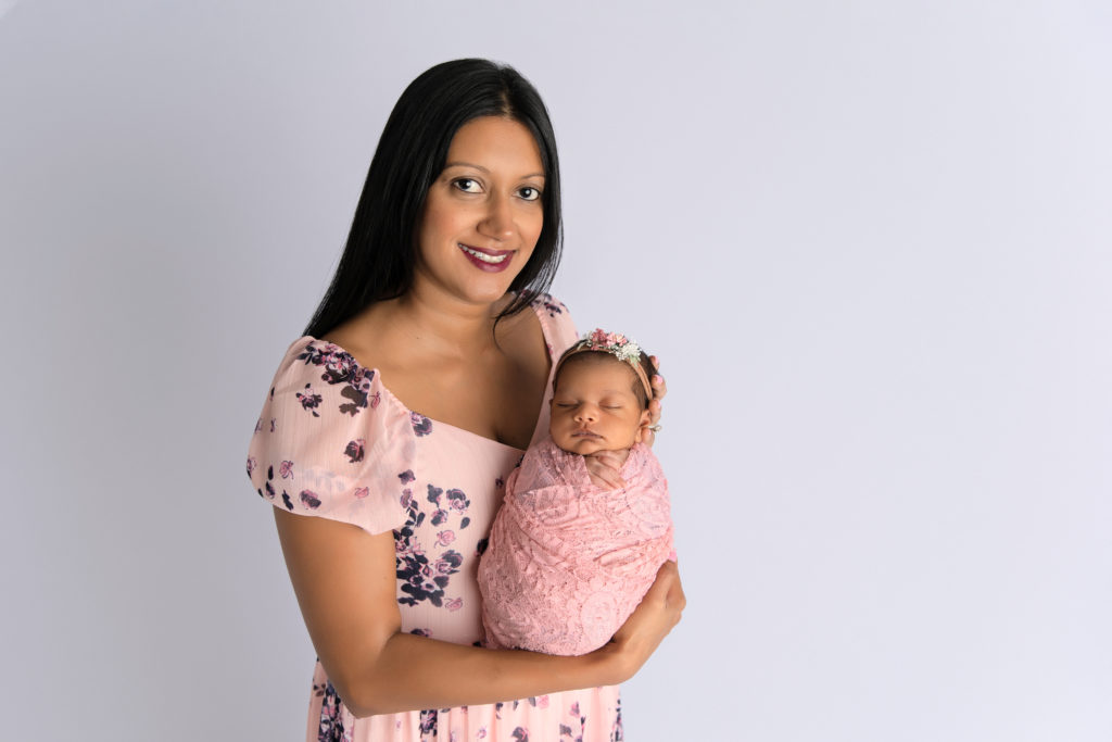 mother holds newborn girl in pink wrap