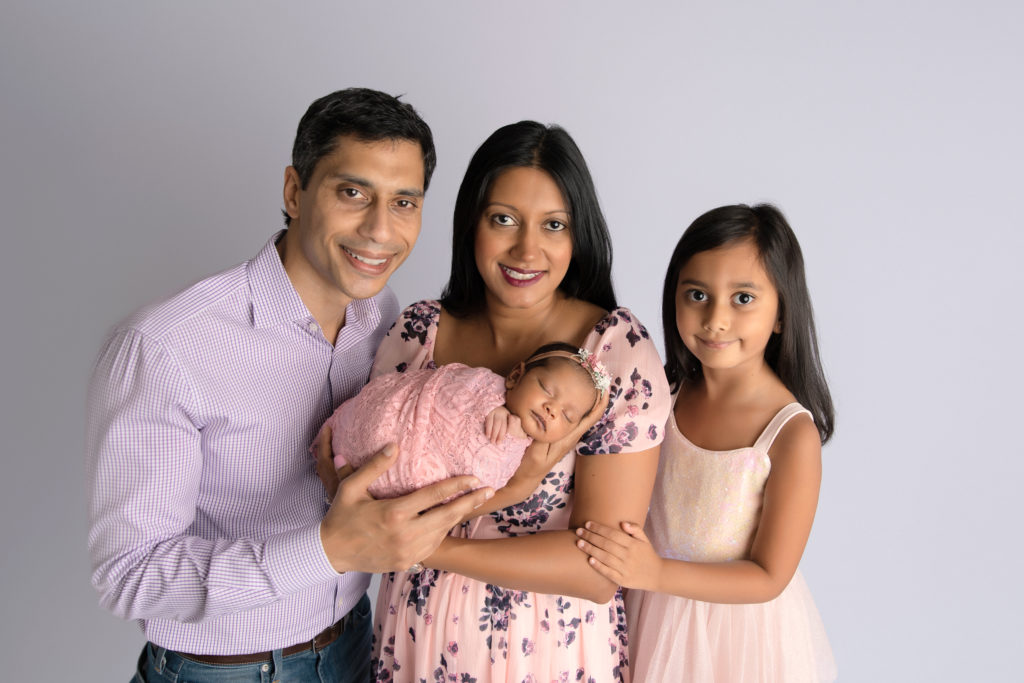 parents and sister pose with newborn girl