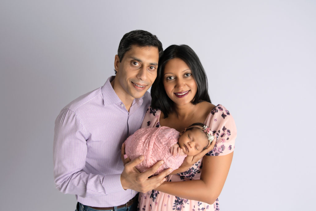 parents hold newborn girl in pink wrap