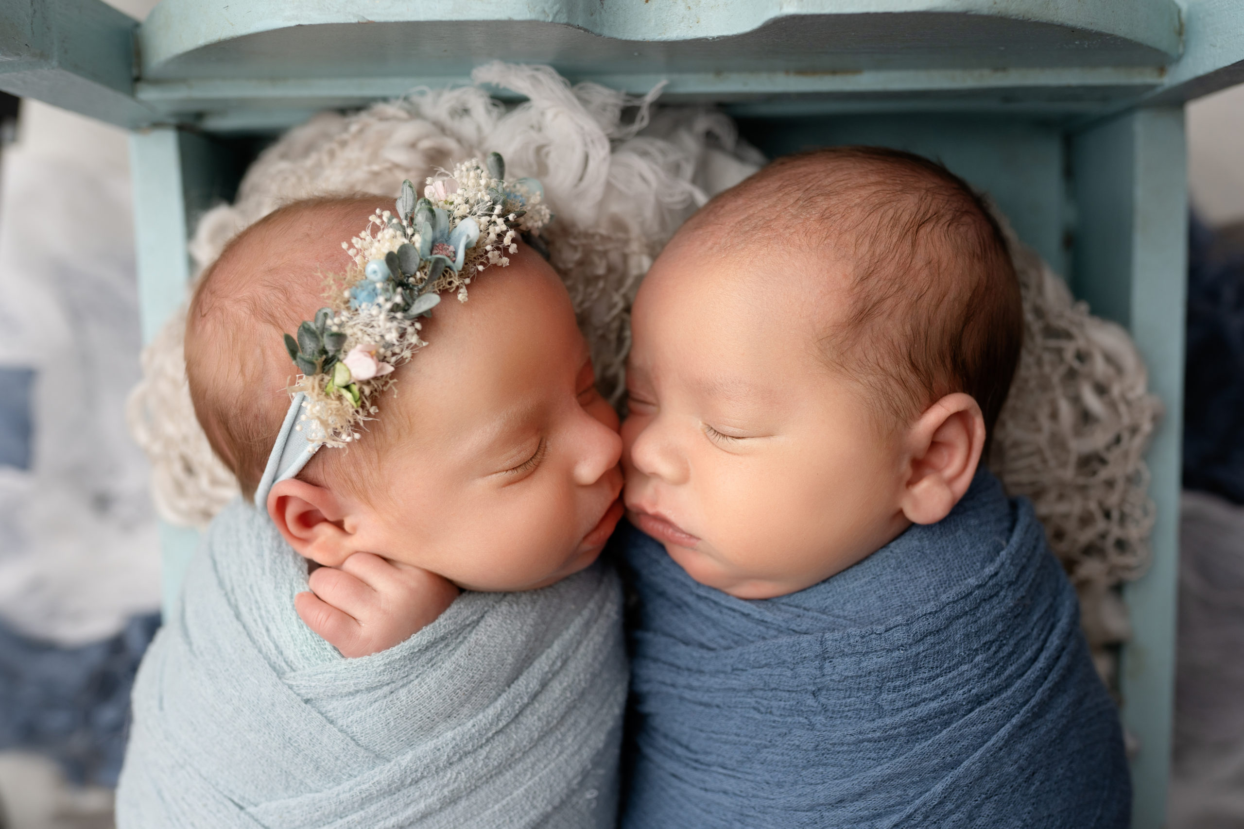 newborn twins lay wrapped with faces touching