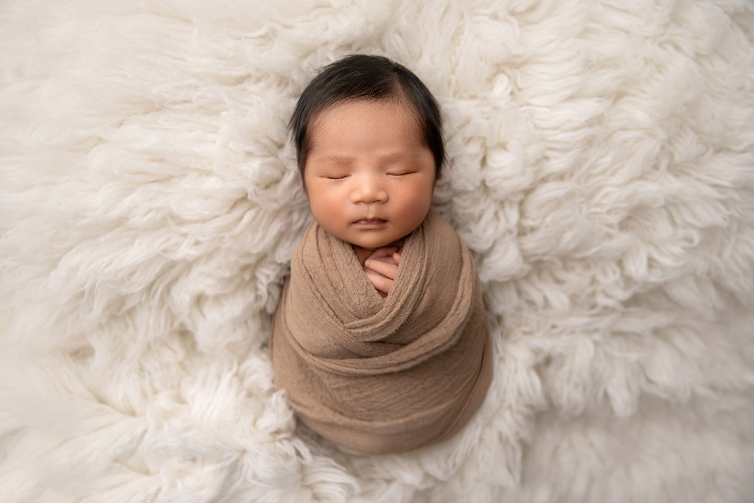 baby boy sleeping wrapped in taupe