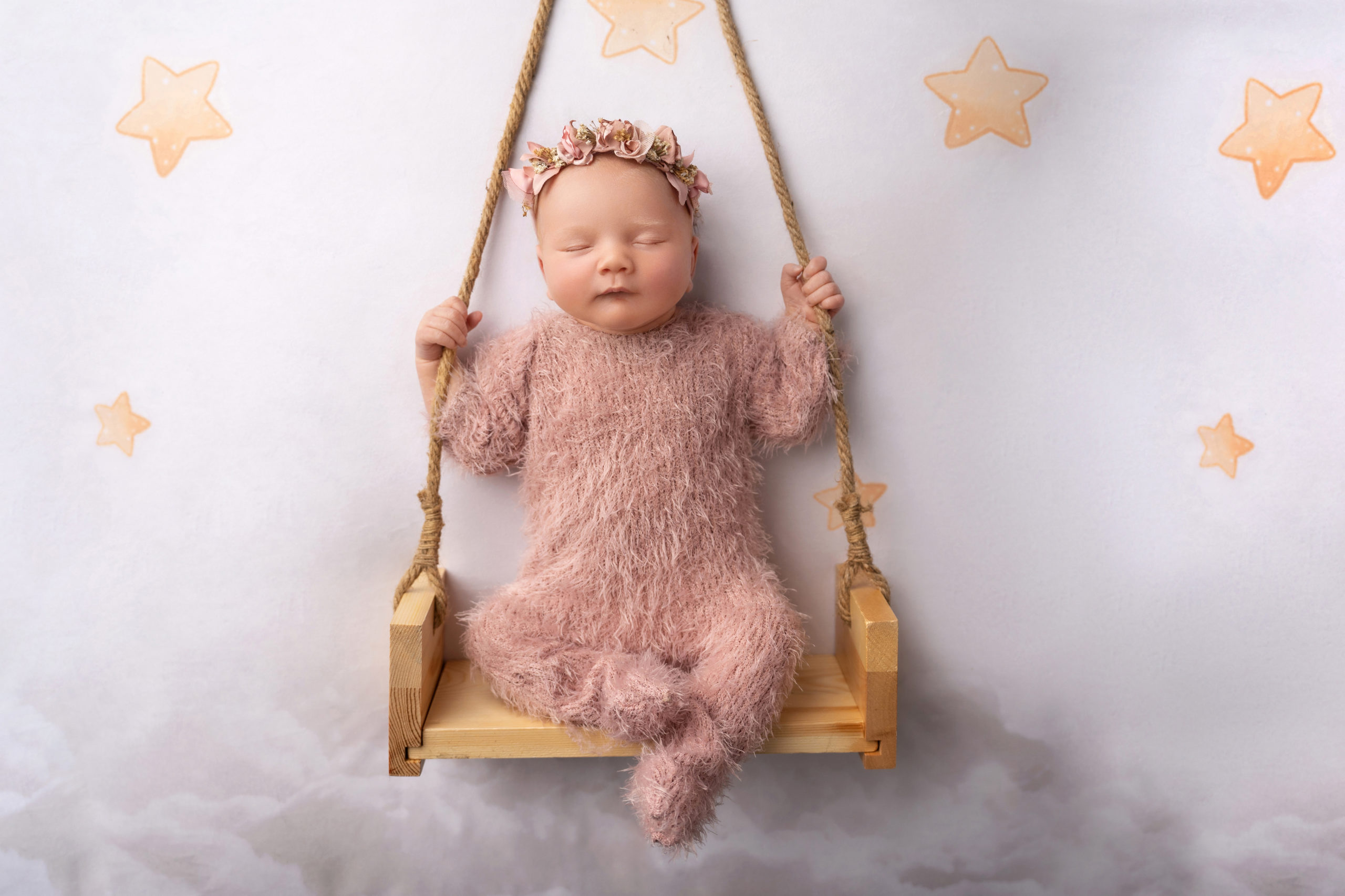baby girl posed in swing set up with stars surrounding